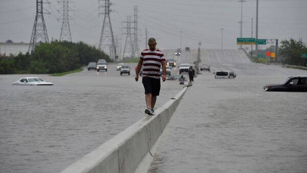 Человек идет по разделительной полосе затопленного шоссе в Хьюстоне, штат Техас, США - Sputnik Грузия