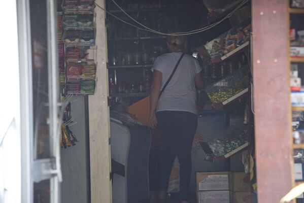 Женщина осматривает помещения в магазине, пострадавшем от взрыва - Sputnik Грузия