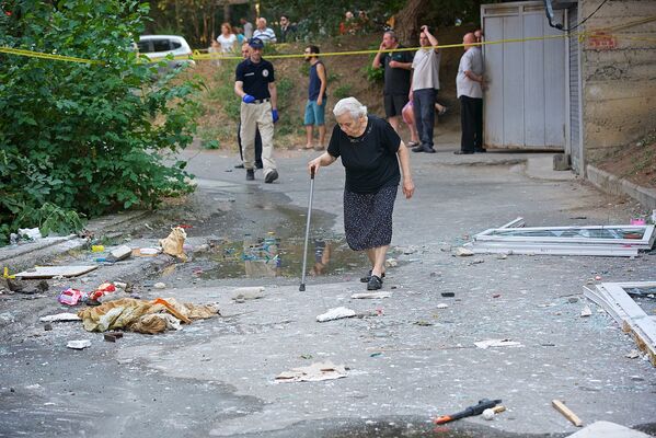 Жительница дома, в одной из квартир которого произошел взрыв природного газа, идет по двору, усыпанному осколками выбитых взрывной волной стекол - Sputnik Грузия