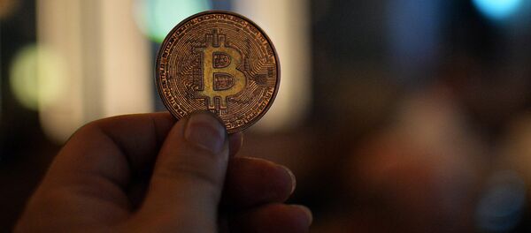 Человек держит в руках сувенирную монету биткоин - Sputnik Грузия