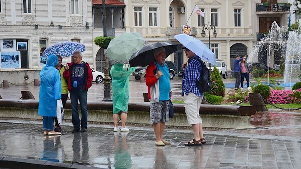 Прохожие с зонтиками идут по одной из улиц Батуми после дождя - Sputnik Грузия