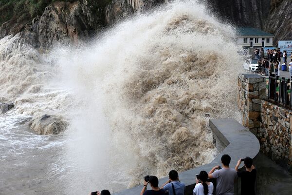Люди наблюдают за гигантской волной на набережной во время приближения тайфуна Талим к Венлингу, провинция Чжэцзян, Китай - Sputnik Грузия