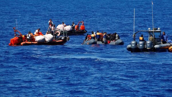 Мигранты на резиновой лодке спасаются организацией SOS Mediterranee во время операции поиска и спасания - Sputnik Грузия