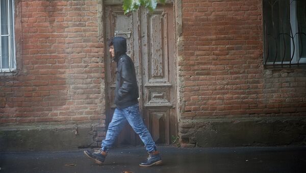 Человек идет по одной из тбилисских улиц в дождь - Sputnik Грузия