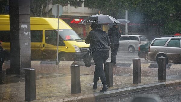 Женщина с зонтом переходит дорогу в дождь - Sputnik Грузия
