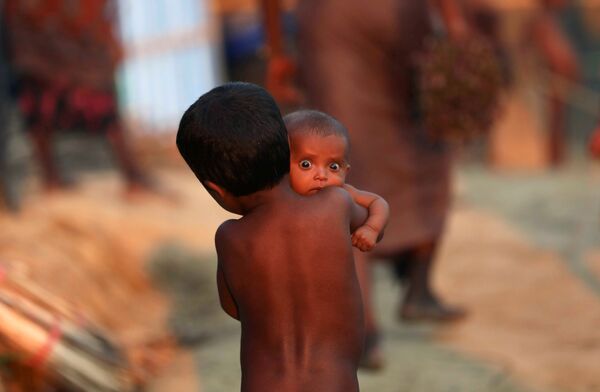 Ребенок рохинья несет младенца в лагере беженцев в Паланге Хали около Базара Кокса, Бангладеш - Sputnik Грузия