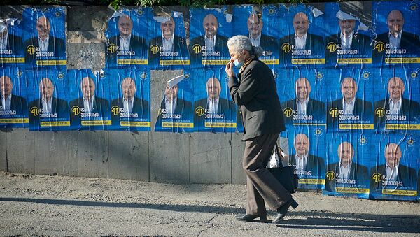 Женщина идет по одной из тбилисских улиц мимо предвыборных плакатов - Sputnik Грузия