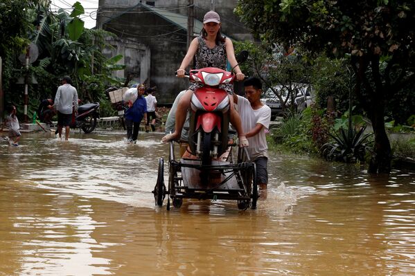 Во Вьетнаме произошло сильное наводнение. На фото - местные жители помогают друг другу переправиться через затопленную дорогу в Ханое - Sputnik Грузия