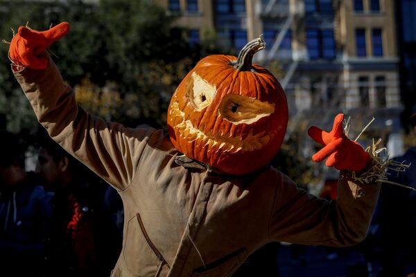 Человек в маскарадном костюме и с ужасающей тыквой на голове гуляет по центру Нью-Йорка во время празднования Хэллоуина - Sputnik Грузия