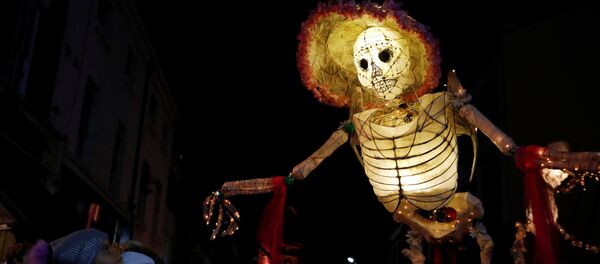 Прохожие смотрят на громадную светящуюся фигуру скелета во время фестиваля фонарей на празднике Хэллоуин в Ливерпуле, Великобритания - Sputnik Грузия