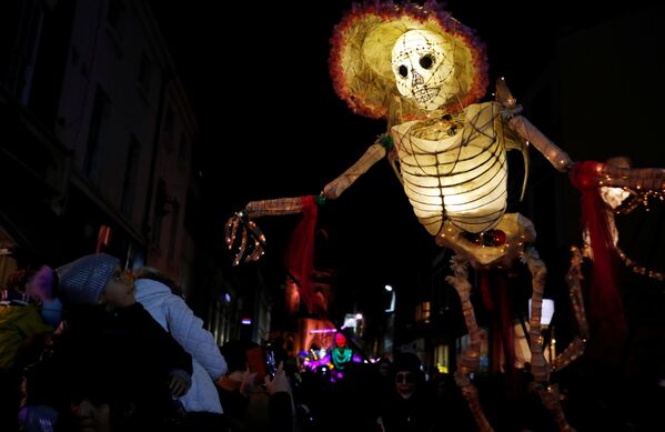 Прохожие смотрят на громадную светящуюся фигуру скелета во время фестиваля фонарей на празднике Хэллоуин в Ливерпуле, Великобритания - Sputnik Грузия