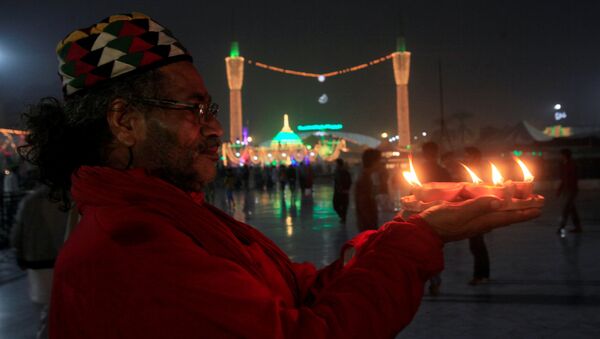 Житель Пакистана держит в руках горящие свечи - Sputnik Грузия
