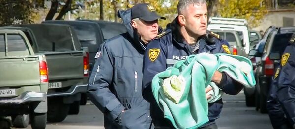 Спецназовец выносит ребенка из зоны спецоперации в Тбилиси - Sputnik Грузия