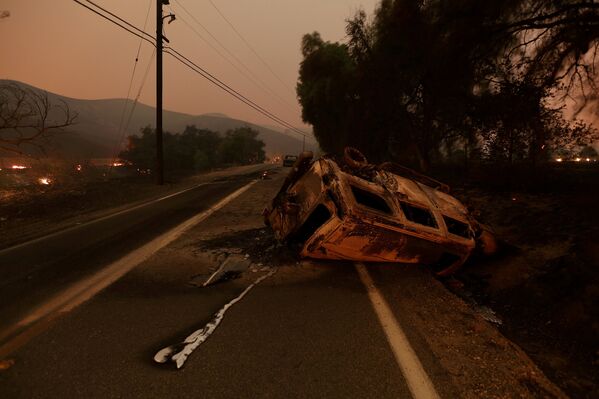 У многих жителей в огне сгорело имущество, машины, вещи. Сгоревшая в результате лесного пожара в Калифорнии машина лежит посреди дороги на шоссе у Санта-Паулы - Sputnik Грузия