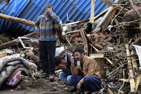 Жители на фоне разрушенных зданий после бурного паводка в Иране. Фото сделано 15 апреля 2017 года - Sputnik Грузия