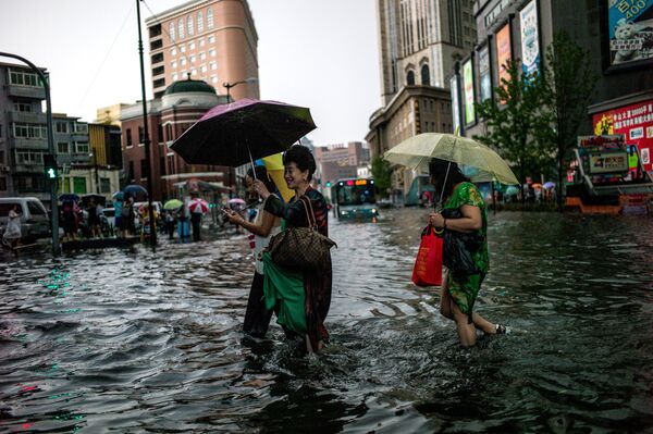Люди на затопленной улице китайского города Шэньян. Снимок сделан 14 июля 2017 года - Sputnik Грузия