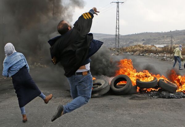 Участники акций протеста в Палестине забрасывают камнями представителей израильских сил безопасности неподалеку от города Рамаллах на Западном берегу реки Иордан - Sputnik Грузия