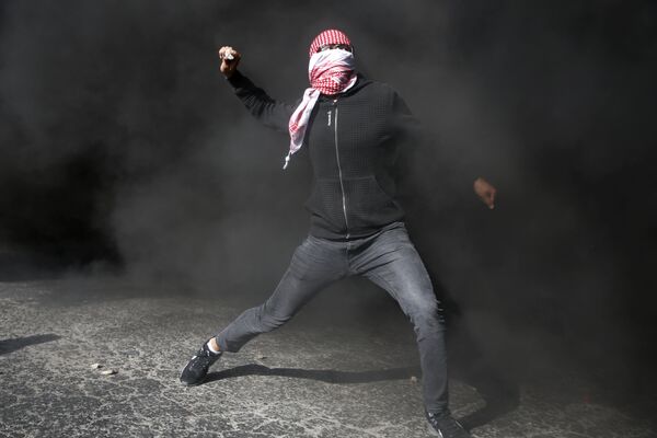 Один из участников акций протеста в Газе забрасывает камнями израильских полицейских - Sputnik Грузия
