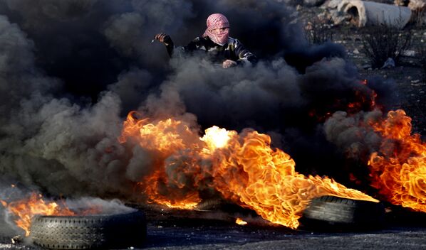 Участники акций протеста в Палестине строят баррикады в Секторе Газа и жгут покрышки. Из клубов дыма, оставаясь невидимыми, они забрасывают камнями израильских полицейских. Это фото сделано у города Рамаллах на Западном берегу реки Иордан - Sputnik Грузия