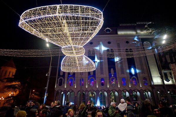 Церемония зажжения огней на большой новогодней елке у парламента Грузии сопровождалась настоящим световым шоу - лучи прожекторов были направлены на здание напротив - Sputnik Грузия