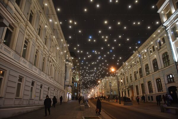 На некоторых московских улицах буквально зажглось звездное небо - между домами растянулись паутины ярких гирлянд. На фото - новогодняя иллюминация на улице Большая Дмитровка в Москве - Sputnik Грузия