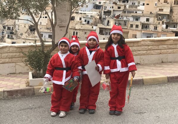 Дети в красных новогодних колпачках, выходя из монастыря святой Феклы в Маалюле, наполняют своим присутствием опустошенный сирийский город рождественским настроением - Sputnik Грузия
