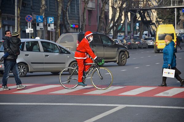 Санта-Клаус в повозке с оленями - классический образ, однако в наше время велосипед может оказаться более эффективным средством передвижения, тем более по оживленным улицам в дневное время - Sputnik Грузия