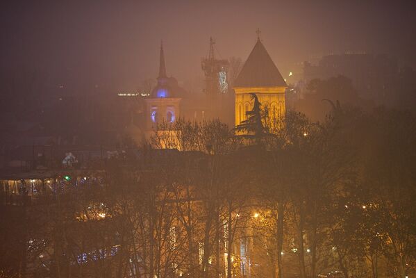Туман преобразил Тбилиси - город потерял свои привычные очертания, сразу став таинственным и словно сказочным. На фото справа - купол храма Сиони - Sputnik Грузия