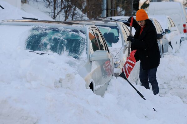 Женщина очищает свою машину от снега после шторма Грейсон в Бостоне, штат Массачусетс, США - Sputnik Грузия