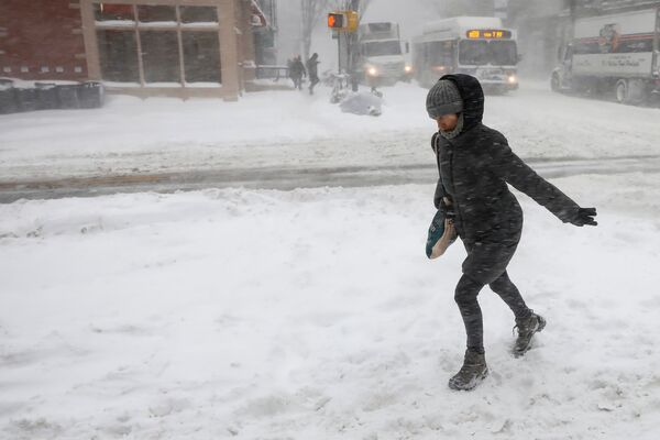 Женщина идет по улице в районе Бруклина против сильного ветра во время шторма Грейсон в Нью-Йорке, США - Sputnik Грузия