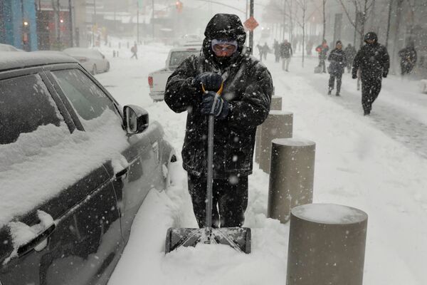 Человек пытается очистить свою машину от снега после снежной бури в Нью-Йорке, США - Sputnik Грузия