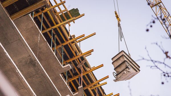 Подъемный кран поднимает груз на строительстве нового многоэтажного жилого дома в грузинской столице - Sputnik Грузия