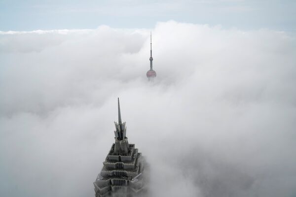 Верхушки небоскребов Восточная жемчужная башня и Башня Цзинь Мао (слева) возвышаются над облаками в сильный туман в финансовом районе Пудун в Шанхае. Снимок сделан из Шанхайского всемирного финансового центра, Китай - Sputnik Грузия