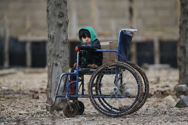 Сирийский ребенок сидит на инвалидной коляске на пограничном переходе Онкупинар с Сирией, на окраине города Килис, Турция. Он и его семья решили укрыться на территории Турции после начала боевых действий турецкой стороны против формирований курдов в сирийском анклаве Африн - Sputnik Грузия