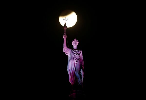 Впервые за 35 лет совпали несколько небесных явлений - Голубая кровавая луна, Суперлуние и лунное затмение. Так спутник земли выглядел этой ночью на фоне статуи на железнодорожном вокзале в Мумбаи, Индия - Sputnik Грузия