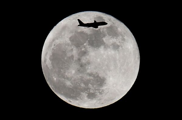 Пассажирский самолет пролетает на фоне полной Луны во время Суперлуния - вид из Лондона, Великобритания - Sputnik Грузия