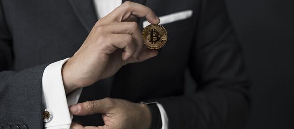 Бизнесмен держит в руках монету биткойн - Sputnik Грузия