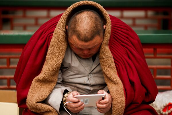 Монах со смартфоном в буддийском храме в парке Бадачу в Пекине во время весеннего праздника по случаю наступления Года Собаки по китайскому календарю - Sputnik Грузия
