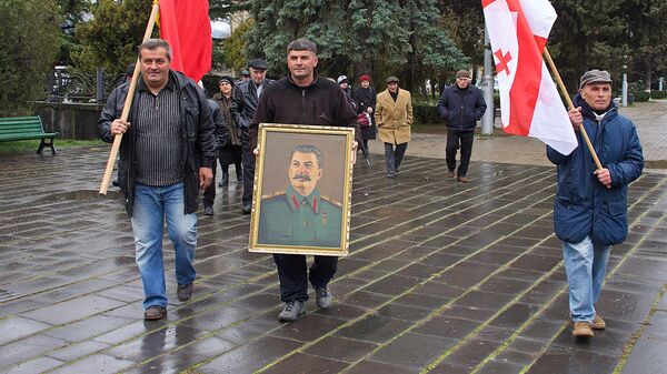 Так портретом Сталина и Красным знаменем, а также флагом независимой Грузии сторонники Вождя народов шли по городу Гори - Sputnik Грузия