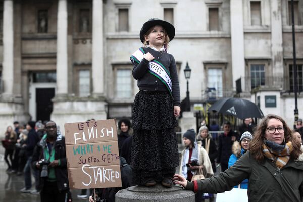 სუფრაჟისტულად ჩაცმული პატარა გოგონა ლონდონში გამართულ ღონისძიებაზე March4Women. სუფრაჟისტები XIX საუკუნის ბოლოსა და XX საუკუნის დასაწყისში პოლიტიკურ და ეკონომიკურ ცხოვრებაში ქალთა დისკრიმინაციის წინააღმდეგ გამოდიოდნენ - Sputnik საქართველო
