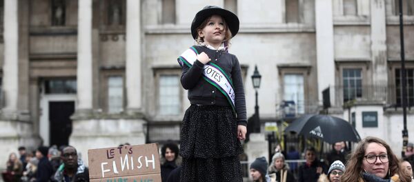 სუფრაჟისტულად ჩაცმული პატარა გოგონა ლონდონში გამართულ ღონისძიებაზე March4Women. სუფრაჟისტები XIX საუკუნის ბოლოსა და XX საუკუნის დასაწყისში პოლიტიკურ და ეკონომიკურ ცხოვრებაში ქალთა დისკრიმინაციის წინააღმდეგ გამოდიოდნენ - Sputnik საქართველო