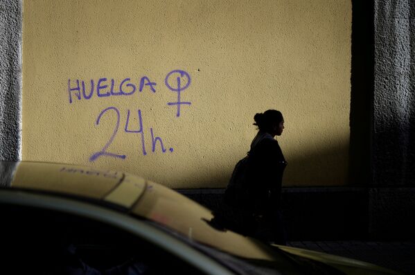 Женщина идет по улице в испанском городе Бильбао мимо стены с граффити движения Удар. 24 часа и символом борьбы за гендерное равенство. Участницы движения с помощью социальных сетей призывали женщин принять участие в массовой забастовке в Международный Женский день - Sputnik Грузия