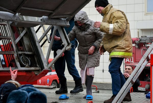 Сотрудники пожарной охраны МЧС РФ помогают посетителям выбраться из торгового центра Зимняя вишня в Кемерово во время пожара - Sputnik Грузия