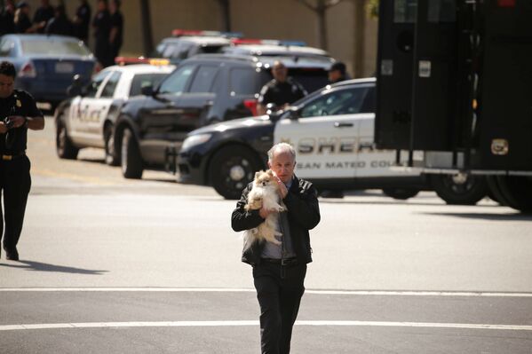 На место ЧП сразу прибыли десятки полицейских экипажей. На фото - офицер полиции спасает собаку и несет ее владельцу у здания штаб-квартиры Youtube в Сан-Бруно в Калифорнии, где была стрельба - Sputnik Грузия
