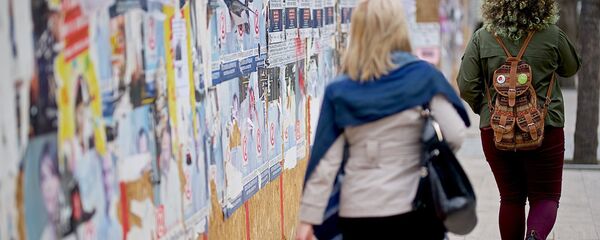 Женщины идут по улице вдоль забора, на  котором наклеены предвыборные плакаты - Sputnik Грузия