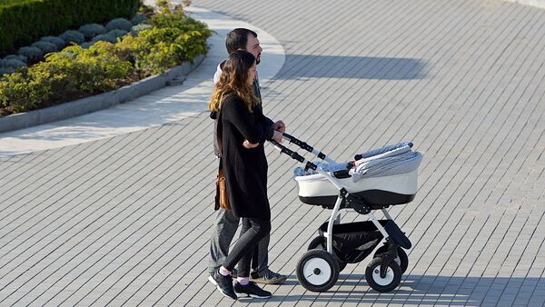 Молодые родители гуляют с ребенком в коляске - Sputnik Грузия