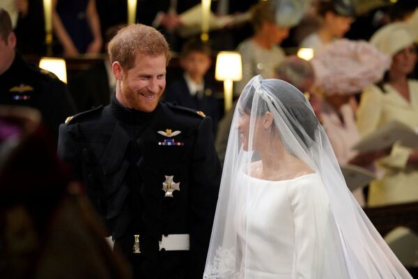 Принц Гарри смотрит на Меган Маркл после ее прибытия на свадебную церемонию. Принц Гарри был в черной военной форме полка дворцовой кавалерии. Невеста выбрала для венчания белое платье от Givenchy с открытыми плечами и длинной фатой - Sputnik Грузия