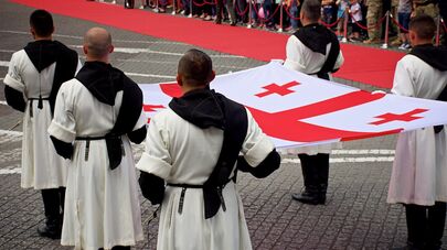 Военнослужащие в грузинской национальной одежде держат флаг Грузии