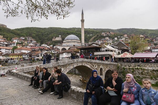 Ново и интересно - Lonely Planet советует посетить Косово. На фото - люди сидят рядом с каменным мостом с видом на город Призрен - Sputnik Грузия