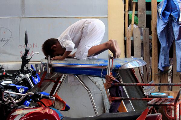Мальчик молится на мотоциклетной кабине во второй день Рамадана у храма в Маниле, Филиппины - Sputnik Грузия